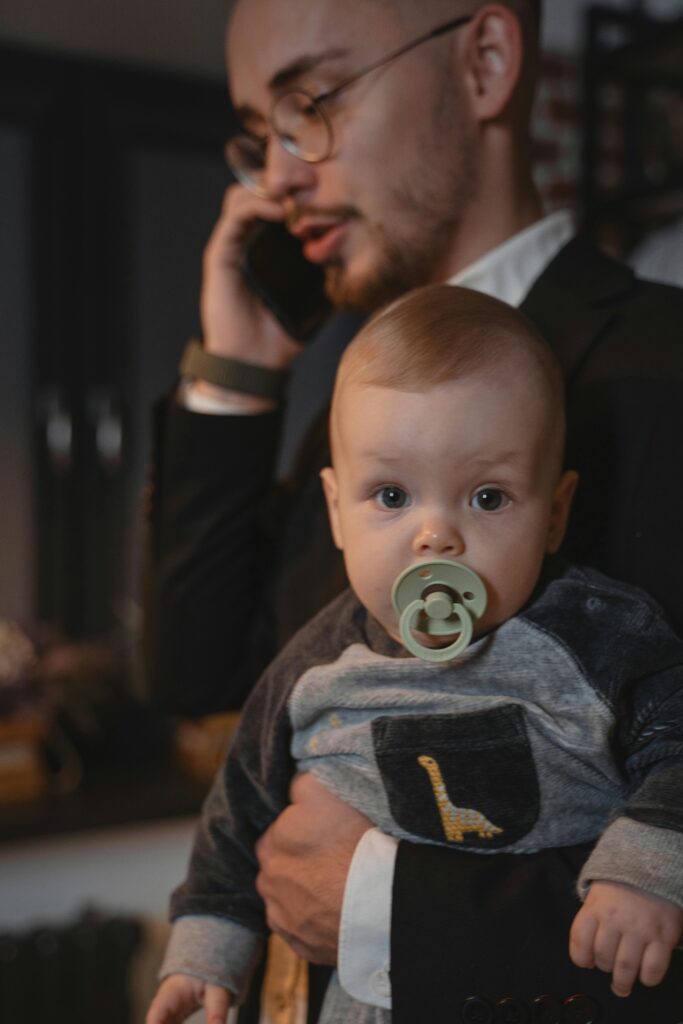 A father holding a baby while on a phone call, illustrating work-life balance.